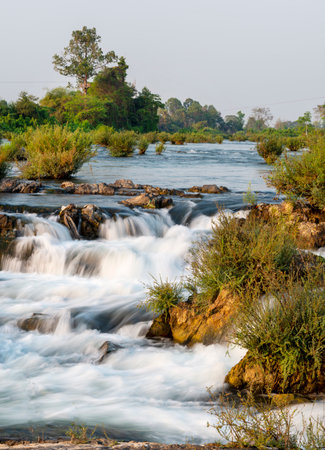 At sunset.Sunlight shining on rocks,next to blurred movement of water,rushing by,at the main waterfalls and rapids of Don Khon island.の写真素材