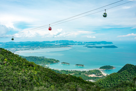 Cable car gondolas travel to and fro the Middle and Upper stations,against a beautiful backdrop of Lankawis countryside,coastline and tree covered mountain peaks,a major tourist destination.の写真素材