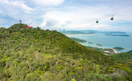 Cable car gondolas travel to and fro the Middle and Upper stations,against a beautiful backdrop of Lankawis countryside,coastline and tree covered mountain peaks,a major tourist destination.の写真素材