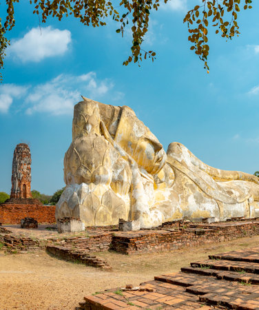 Laying in repose in the afternoon sun,under blue skies,the huge stone statue of Buddha is a popular tourist destination,in the former ancient Siamese temple capital,close to Bangkok.の写真素材