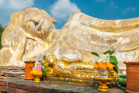 Laying in repose in the afternoon sun,under blue skies,the huge stone statue of Buddha is a popular tourist destination,in the former ancient Siamese temple capital,close to Bangkok.の写真素材