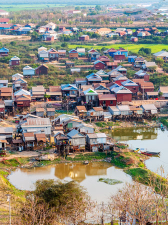 In late afternoon sunlight,standing next to a water ponds,simple dwellings viewed from Phnom Kraom hilltop temple,the area becomes flooded in rainy season.の写真素材
