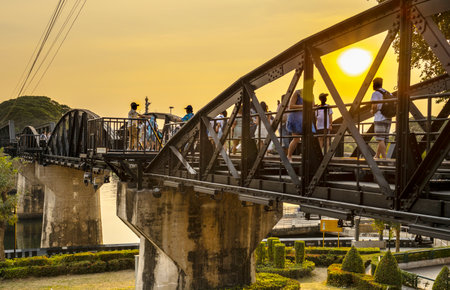The setting sun pours warm golden light across the famous landmark, part of the Thai-Burma Railway...