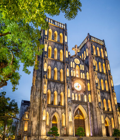 19th-century Neo-Gothic style,Catholic church,with a facade of many small arches,glowing with lights after sunset,a popular tourist destination and major historical landmark in central Hanoi.の写真素材
