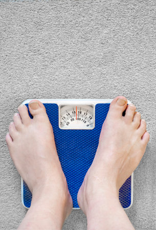 Users eye view of domestic spring scales,looking down at the bare feet and legs of a white male,to...