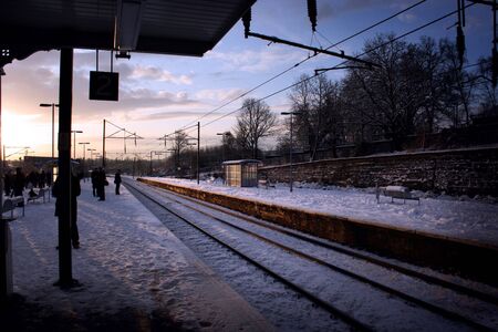 Passengers waiting for train on snow covered platformの写真素材