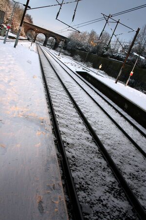 Snow covered train platform with bridge in distance の写真素材