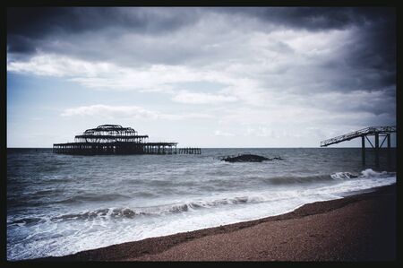 Remains of west pier, with waves crashing on shore, Brighton, England, UKの写真素材