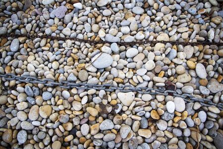 Rusty chain laid on pebbles, Chesil beach, Weymouth, Dorsetの写真素材