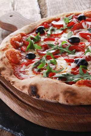 whole fresh baked pizza with olives and salamiの写真素材