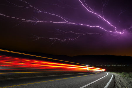 Lighting strike with long exposure traffic trails under stormy sky.の写真素材