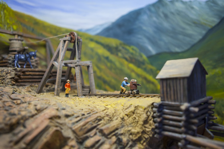 Mining model with tiny people, head frame and ore cart tracks. Shallow depth of field with focus on man pushing ore cart.の写真素材