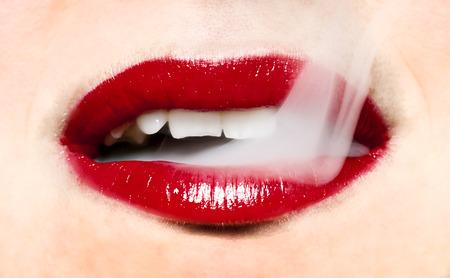 Smoke coming from mouth. Woman with bright red lips.の写真素材
