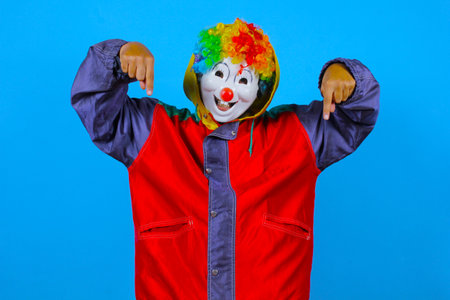Clown in a red jacket and a clown wig on a blue backgroundの写真素材