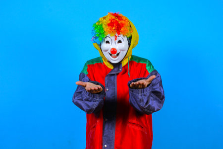 Clown in red jacket and colorful wig on blue background, studio shotの写真素材