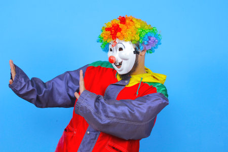 Clown with red jacket and colorful wig isolated on blue background.の写真素材