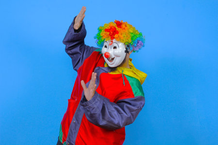 Portrait of a funny clown in a clown costume on a blue backgroundの写真素材