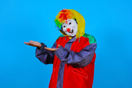 Clown in a red jacket and a clown wig on a blue backgroundの写真素材