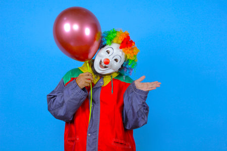 Portrait of a funny clown with a balloon on a blue backgroundの写真素材