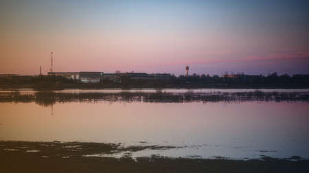 calm waveless flood water on meadow in Latvia, beautiful spring evening sunset, clear sky, factory...