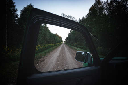 looking through window of opened car door, framing, endless straight forest road