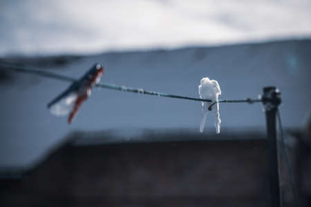 Clothespin in snowflakes in winter. Winter day and clothesline in the snow against the background of the skyの写真素材