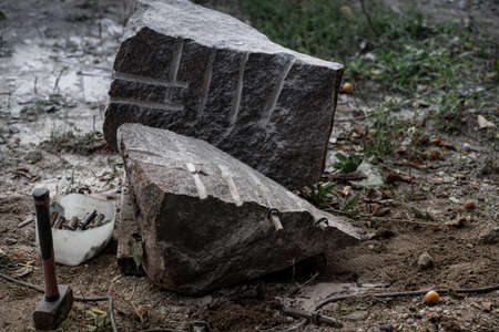 splitted granite boulder, hammer, drill holes and metal wedgesの写真素材