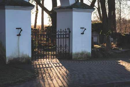Gate columns in Latvian cemetery, nice shadows play from sunset light through metal fence. BÄrzes kapi, Latvia, Zemgaleの写真素材