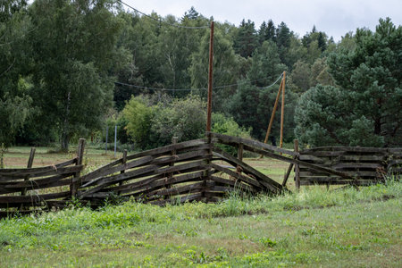 Old  broken skew wooden fence on the meadow in the village, Latviaの写真素材