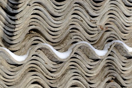 Pile of asbestos roof tiles with snow in the winter. Wavy industrial background texture.の写真素材