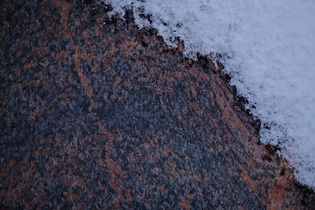Close up of natural stone surface covered with snow and ice in winterの写真素材
