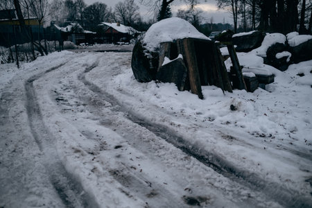 Snowy winter road in the village. Traces of cars on the road.の写真素材