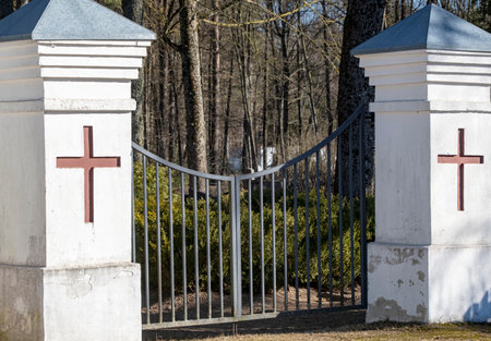 Cemetery gate with christian cross of the spring forest.