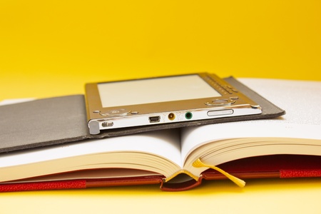 pile of traditional books and electronic book on orange background