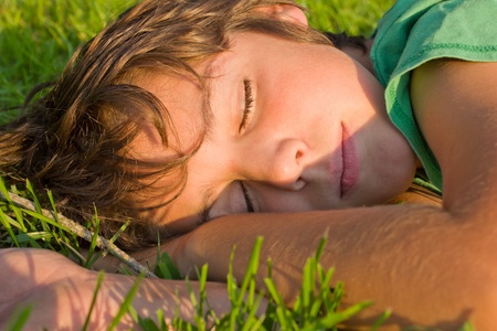 teenager boy relaxing on green grass lawnの写真素材