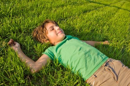 teenager boy relaxing on green grass lawnの写真素材