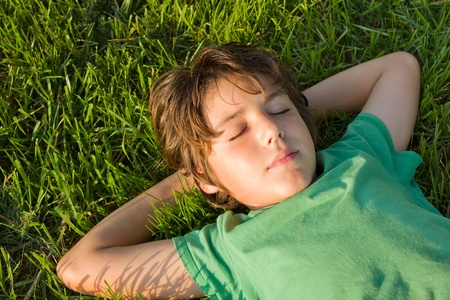 teenager boy relaxing on green grass lawnの写真素材