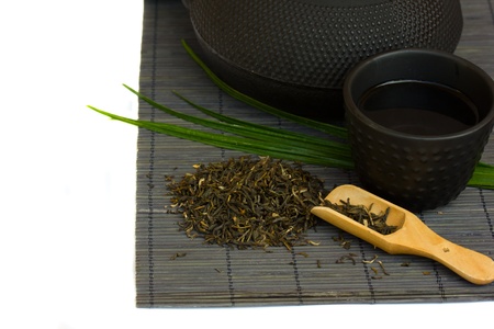 pile of dry green tea with tea bowl isolated on white backgroundの写真素材