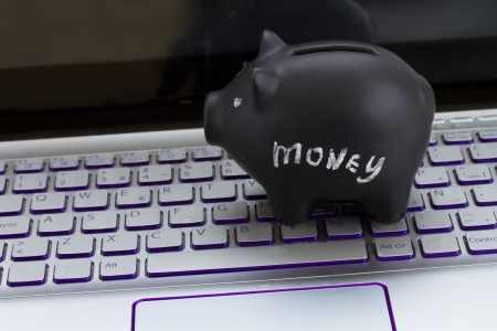 internet shopping concept - black piggy bank on laptop keyboardの写真素材