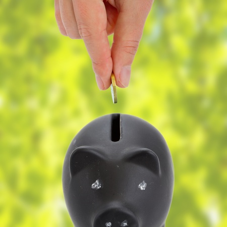 Saving  Hand putting a coin into piggy bank の写真素材