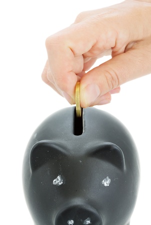 Saving  Hand putting a coin into piggy bank の写真素材
