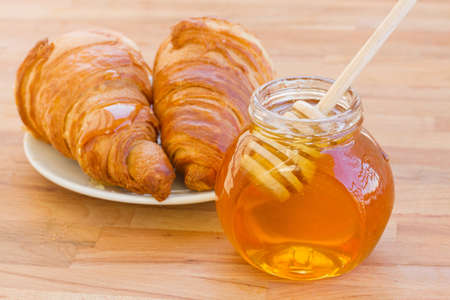 breafast with croissants and honey on wooden tableの写真素材