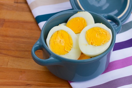 hard boiled eggs in blue pot on wooden tableの写真素材