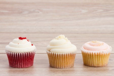 three homemade cupcakes - strawberry, chokolate and vanille on wooden tableの写真素材