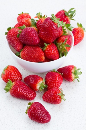 pile of strawberry in plate and on a kitchen tableの写真素材