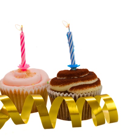 Two cupcakes  with burning candles isolated on white backgroundの写真素材