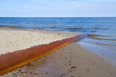 old rusted iron pipe dripping  in clear blue  sea
