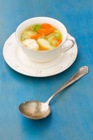 Fish soup with silver spoon on blue wooden tableの写真素材