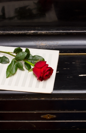 one red rose and note paper on closed vintage black pianoの写真素材