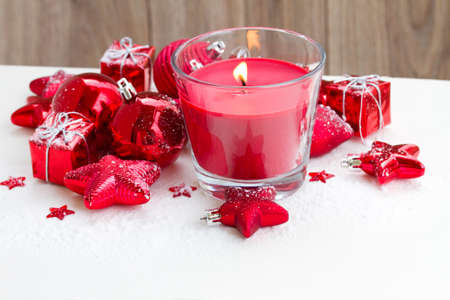 christmas red burning candle  with christmas decorations on snowの写真素材